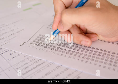 Les élèves hand holding crayon écrivant certains choix sur les feuilles de réponses et mathématiques question feuilles. Les élèves faisant des tests d'examen. examen scolaire Banque D'Images