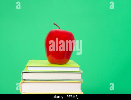 Close up sur des livres reliés avec différentes couvertures colorés empilés avec pomme rouge en haut, fond vert sombre semblable à la craie à l'ancienne administration. Ba Banque D'Images