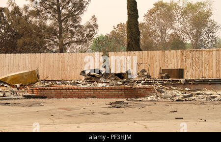 Accueil brûlé à la terre, clôture laissé intact dans la récente tempête de feu feu sauvage à Redding en Californie. La fumée et des cendres dans l'air comme le feu contin Banque D'Images