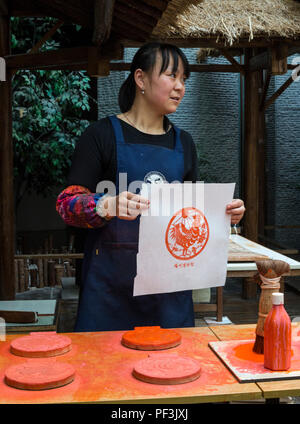 Yangzhou, Jiangsu, Chine. Le Musée de l'impression de bloc de la Chine. Holding Imprimer taillées dans du bloc en bois. Banque D'Images