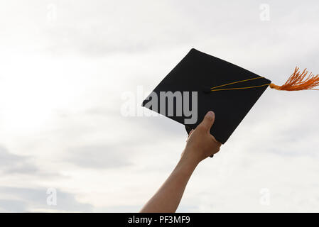 Les mains des diplômés titulaires d'un chapeau noir et d'un gland jaune s'étend vers le ciel. Banque D'Images