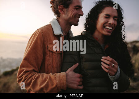 couple voyageant debout dehors ensemble et riant. Homme et femme en vêtements chauds debout sur la montagne et profiter du moment. Banque D'Images