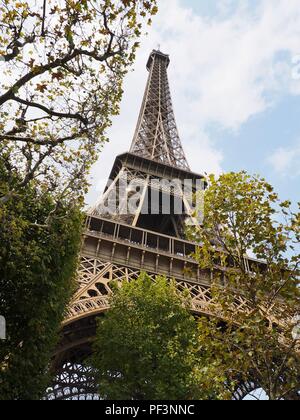 À la recherche jusqu'à la Tour Eiffel encadrée dans la feuilles des arbres d'or Banque D'Images