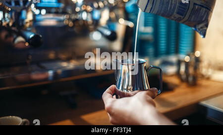 Tablier Barista en verse de crème dans la tasse de café, café comptoir sur l'arrière-plan. Cappuccino professionnel préparation par barman Banque D'Images