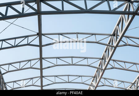 Grand cadre métallique de la toiture de l'entrepôt en construction dans le temps. Banque D'Images