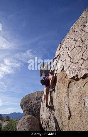 Asian woman rock climber bouldering sur un bloc de granite à la zone d'escalade de babeurre près de Bishop Californie Banque D'Images