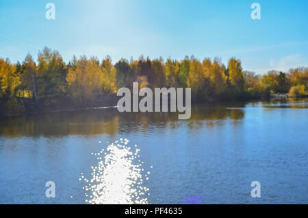 Paysage d'automne forêt floue avec la réflexion dans le lac et le reflet du soleil dans l'eau. Banque D'Images