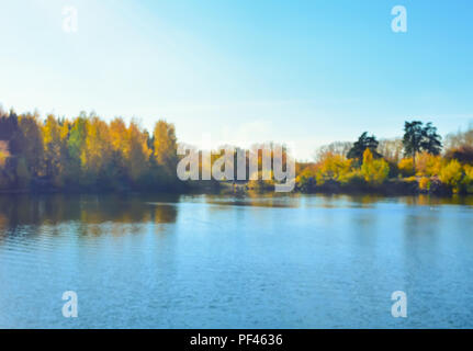 Paysage d'automne forêt floue avec la réflexion dans le lac et le reflet du soleil dans l'eau. Banque D'Images