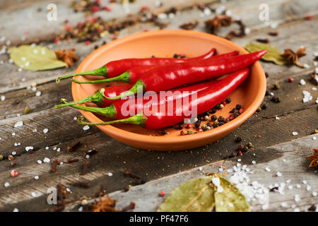 Fresh red hot chili pepper dans un bol avec des épices sur fond rustique en bois Banque D'Images