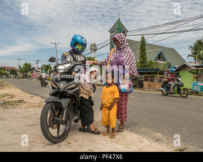 Kaimana, Indonésie - 31 janvier 2018 : la famille indonésienne avec moto dans la rue dans le petit village sur la Papouasie Occidentale Banque D'Images