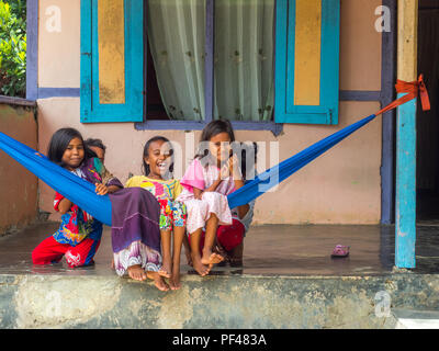 Ambon en Indonésie - 11 Février 2018 : un groupe de jeunes filles de l'Indonésie, dans des vêtements colorés assis sur le hamak dans le petit village de l'île, Banque D'Images