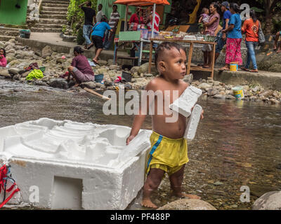 L'île d'Ambon, Indonésie - 11 Février 2018 : Indonesian Garçon jouant dans la rivière sur l'île d'Ambon, Moluques, Maluki Banque D'Images