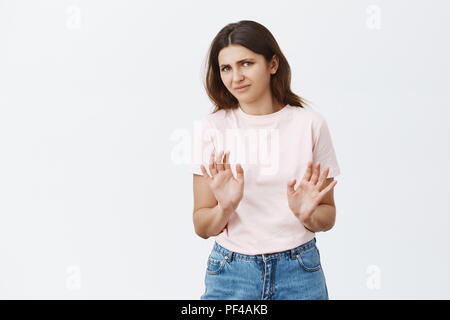 Non merci je refuse. Portrait de mécontent mécontent et intense brunette Femme en rose t-shirt waving palms près de poitrine en refus ou rejet smiling geste gêné et malheureux sur fond gris Banque D'Images