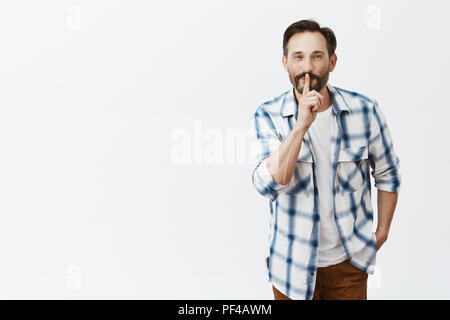 Père fils dit qu'il doit garder secrète de la mère. Portrait de genre et beau mâle mature avec chemise à carreaux, barbe en montrant en disant geste chut chut, tenant l'index sur la bouche Banque D'Images