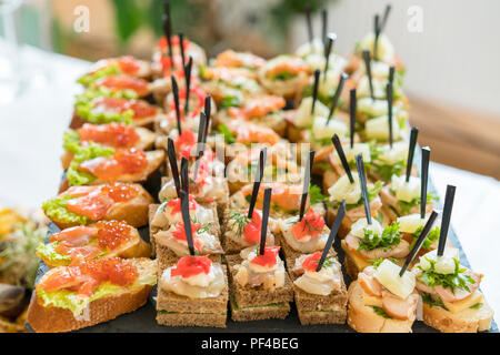 Crostini avec garnitures différentes sur fond de bois. De délicieux hors-d'œuvre. Vue de face. Hors-d'œuvre gastronomique : caviar, venaison, thon et saumon Banque D'Images