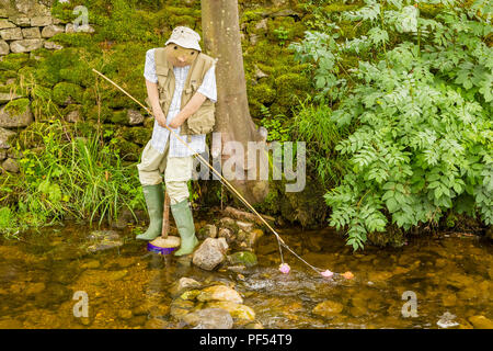 Personnage de Scarecrow d'un pêcheur avec canne, à côté de la rivière Wharfe, lors d'un festival de Scarecrow dans le Yorkshire Dales, Royaume-Uni. Horizontale. Espace pour la copie Banque D'Images