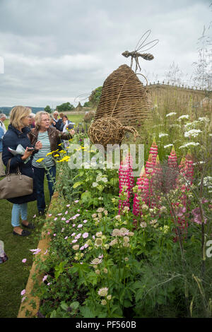 2 Les femmes obtiennent près de sculptures & Plantes à fleurs sur la pièce (de la frontière de la concurrence) - RHS Flower Show de Chatsworth, Derbyshire, Angleterre, Royaume-Uni. Banque D'Images