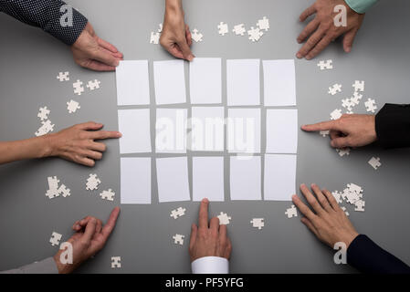 Vue de dessus les mains vides d'affaires touchant des livres blancs disposés sur un tableau gris. Banque D'Images