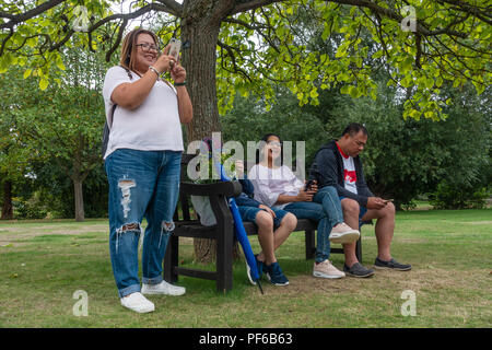 Les amis de s'asseoir ensemble sur un banc sous un arbre dans un parc. Banque D'Images