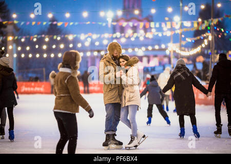 Young couple in love man avec des cheveux blonds aux cheveux longs et la barbe et belle femme s'amuser, date active patinoire sur le Ice Arena dans Banque D'Images