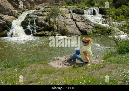 Zhitomir, Ukraine - le 16 juillet 2018. La cascade sur la rivière coule à travers et sur les rochers couverts de lichen et de mousse sur un fond de gr Banque D'Images