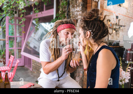 Homme Hippie de rejoindre sa petite amie drinking cocktail Banque D'Images