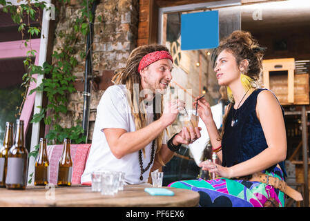 Couple de hippies assis à la table de boire de l'alcool des boissons Banque D'Images