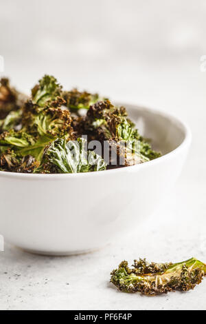 Kale chips dans un bol blanc sur fond blanc. Concept de l'alimentation propre. Devenez-le ! Banque D'Images