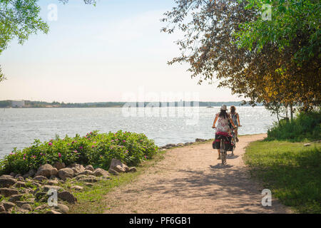 L'île d'Helsinki de l'été, vue sur un matin d'été de deux jeunes femmes à cheval sur une piste cyclable sur l'île de Katajanokka, près d'Helsinki, Finlande. Banque D'Images