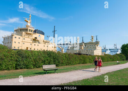 Parc d'Helsinki, vue de deux jeunes femmes finlandaises walking in City Park sur l'île de Katajanokka, avec un groupe d'énormes amarrés à proximité d'Helsinki, brise-glace. Banque D'Images