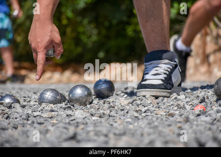 Pétanque player pointant vers le sol, tenant une boule d'acier Banque D'Images