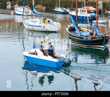 Dunbar, East Lothian, Ecosse, Royaume-Uni, 20 août 2018. UK Soleil dans le port de Dunbar. Deux hommes de quitter le port dans un petit bateau avec des bateaux amarrés, y compris les bateaux de pêche et yachts Banque D'Images