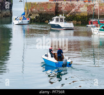 Dunbar, East Lothian, Ecosse, Royaume-Uni, 20 août 2018. UK Soleil dans le port de Dunbar. Deux hommes de quitter le port dans un petit bateau avec des bateaux amarrés, y compris un bateau de pêche et des yachts Banque D'Images