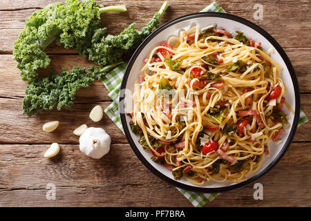 La cuisine italienne : pâtes linguine aux légumes frits, bacon et fromage parmesan close-up sur une plaque sur une table horizontale. haut Vue de dessus Banque D'Images