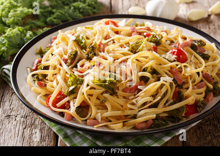 Délicieux avec des pâtes linguine épicées poêlée de chou kale, bacon, tomates, l'ail et le parmesan sur une plaque horizontale sur la table. Banque D'Images