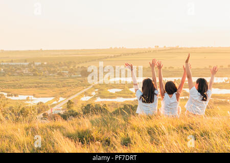 Groupe de trois filles pour le coucher du soleil sur une colline à campagne Banque D'Images