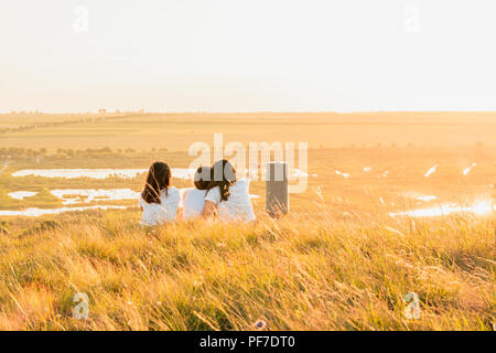 Groupe de trois filles pour le coucher du soleil sur une colline à campagne Banque D'Images