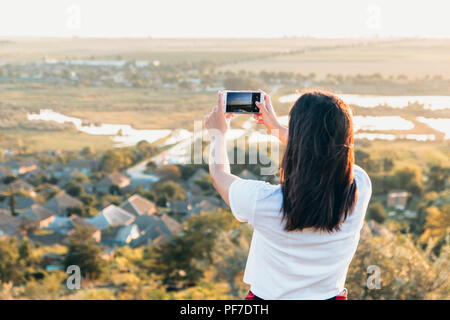 Belle fille à prendre des photos de campagne d'une colline, au coucher du soleil Banque D'Images