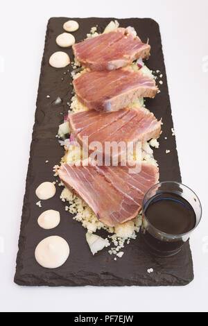 Tataki de thon servi sur une ardoise de forme oblongue avec du couscous et la sauce soja Banque D'Images