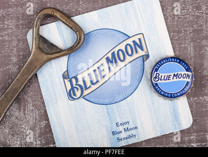 Londres, Royaume-Uni - 10 août 2018:Blue Moon beer coaster avec flacon et l'ouvreur sur fond de bois. Banque D'Images