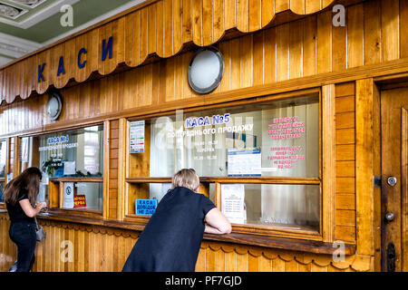 Rivne, Ukraine - 25 juillet 2018 : la gare ferroviaire de fer fer stand avec femme l'achat de billets pour le trajet à partir de la caisse à l'intérieur du bâtiment ancien régime soviétique w Banque D'Images