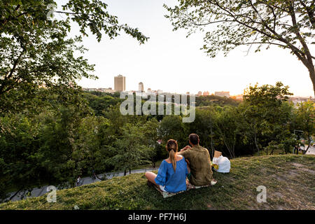 Kiev, Ukraine - le 10 août 2018 : Paysage alley à Kiev capitale au coucher du soleil d'or avec couple sitting on hill à la recherche de pointe à citysc Banque D'Images