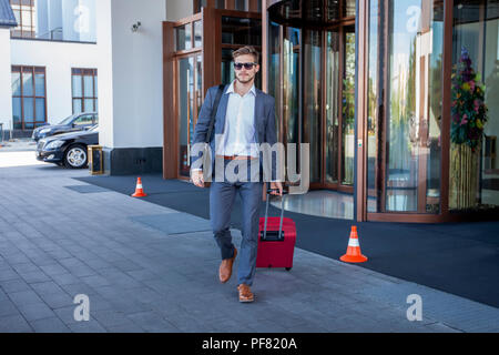 Businessman walking de hall de l'hôtel. Portrait de jeunes cadres avec une valise. Banque D'Images