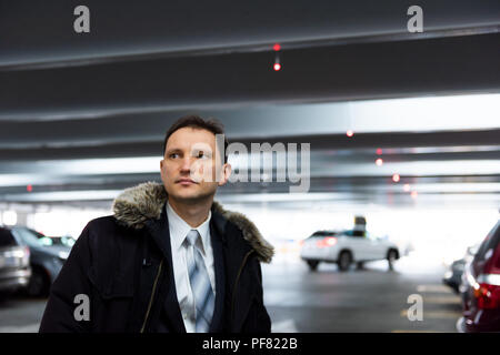 Beau, séduisant jeune homme sérieux stern malheureux libre face portrait debout dans l'intérieur parking en costume et cravate sur pause interview Banque D'Images