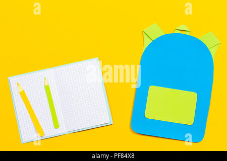 Sac à dos sac d'école, cahiers et crayons papier découpées sur fond jaune. Banque D'Images