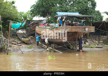 Delta du Mékong ouvriers locaux réparer un bateau en bois le long de la rivière du Mékong Vietnam Banque D'Images