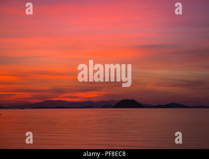 Beau ciel coucher de soleil orange et rose au crépuscule sur le Parc National de Komodo, en Indonésie, avec l'océan dans l'avant-plan. Banque D'Images