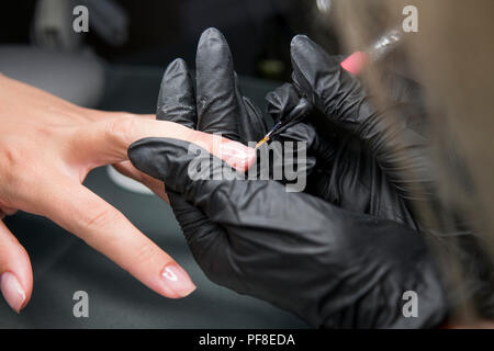 La manucure pédicure permet de procédure et de recouvrement de vernis sur les ongles de la fille dans le salon de manucure . Prise d'un gros plan femme mains in nail salon receiving manicure une par une esthéticienne Banque D'Images