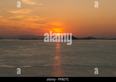 Le soleil se couche sur l'île de Komodo, avec l'océan dans l'avant-plan, le Parc National de Komodo, Indonésie Banque D'Images