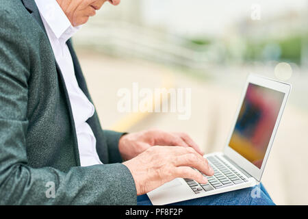 Petit businessman using laptop on street Banque D'Images